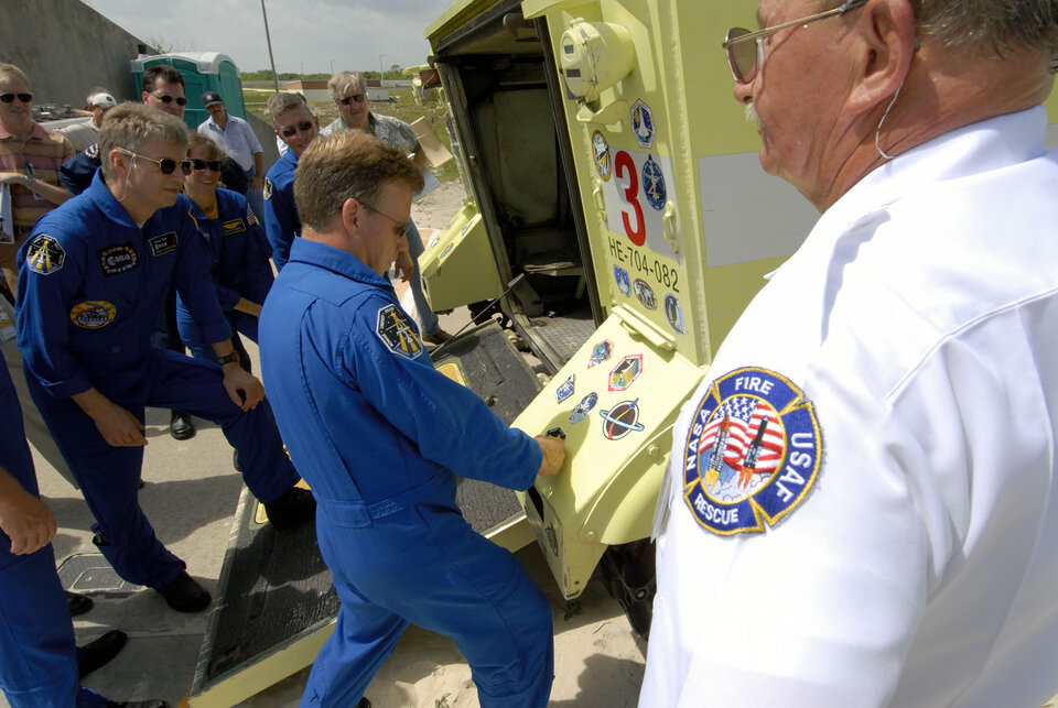 Commander Steven Lindsey applies a mission sticker to a fire rescue vehicle at NASA's Kennedy Space Center