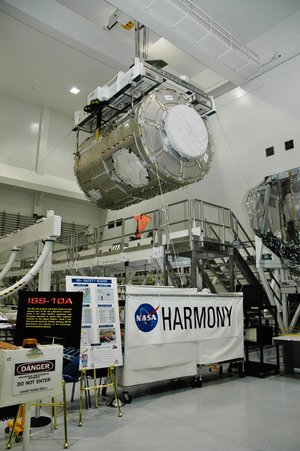 An overhead crane lifts the U.S. Node 2 module, known as Harmony, from its stand.