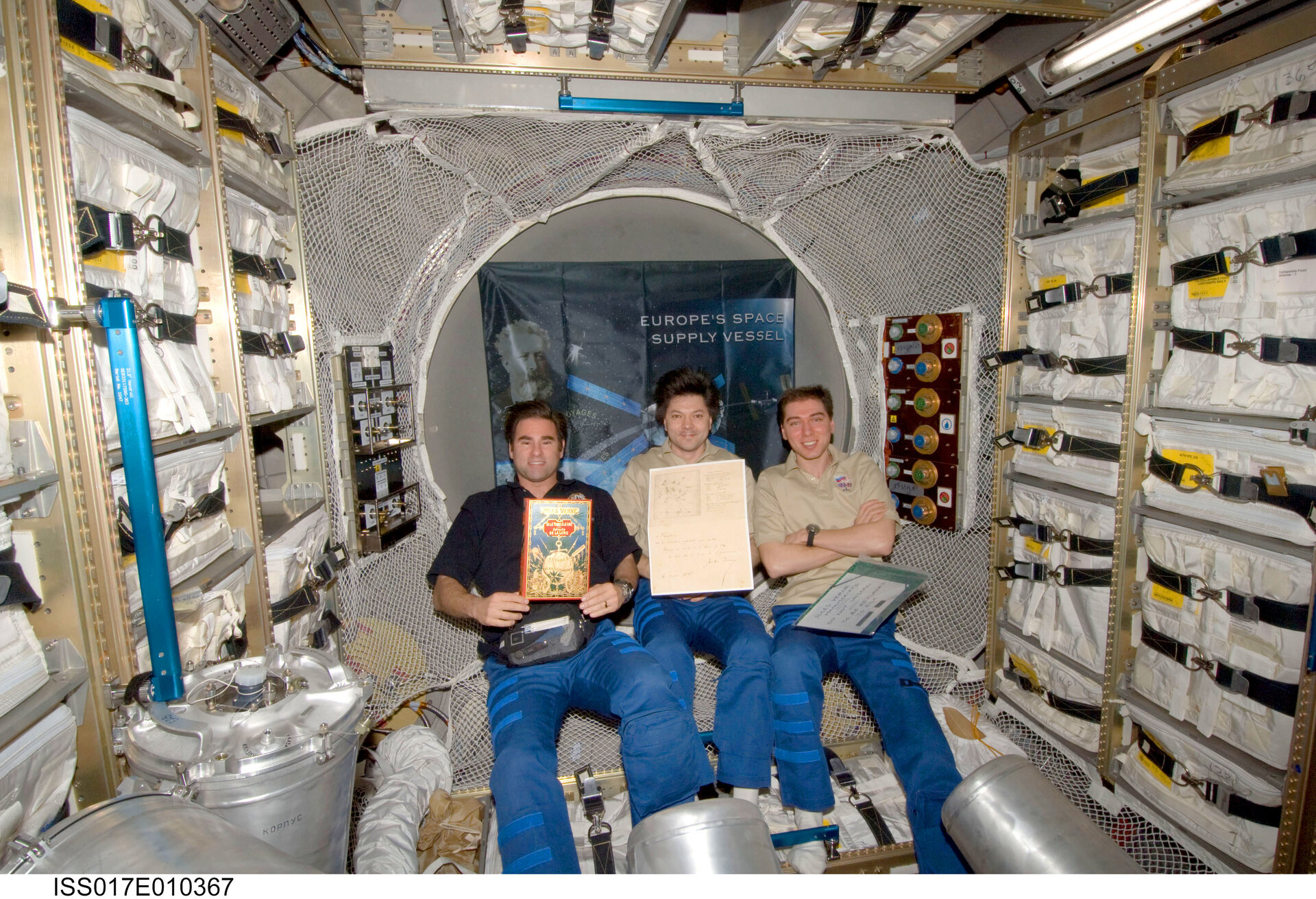 ISS Expedition crewmembers display the Jules Verne book and manuscripts delivered to the ISS