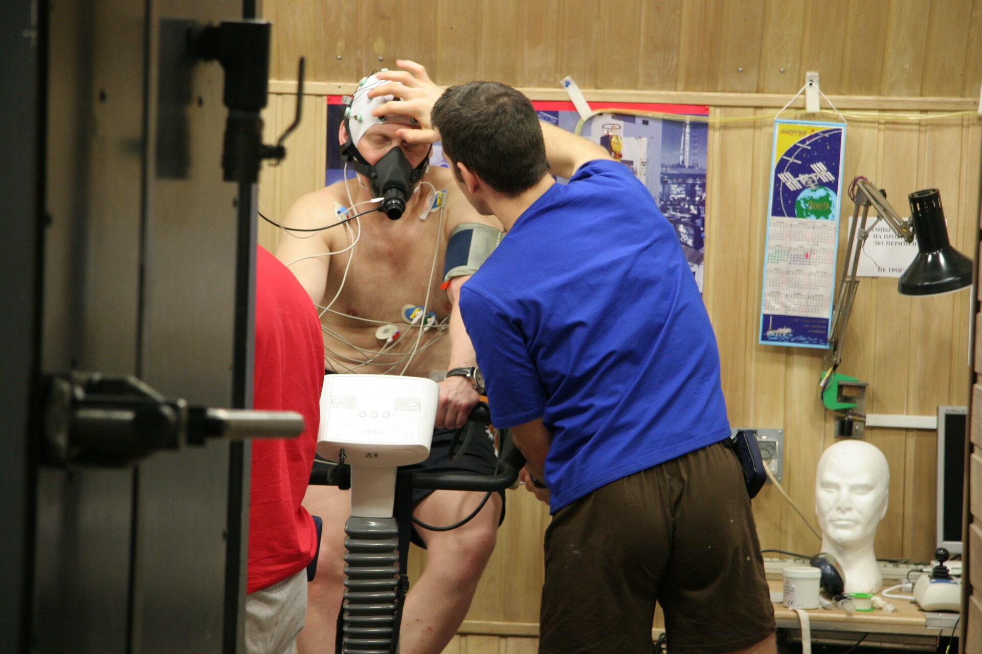 Oliver checks electrodes being used to measure brain activity as Oleg exercises on bicycle ergometer