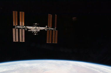ISS backdropped by a blue and white part of Earth