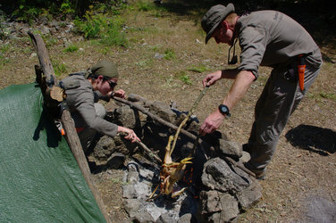 Tim Peake (right) preparing dinner on the campfire