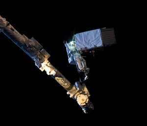 Strapped to a robotic arm holding 385 kg in space at night