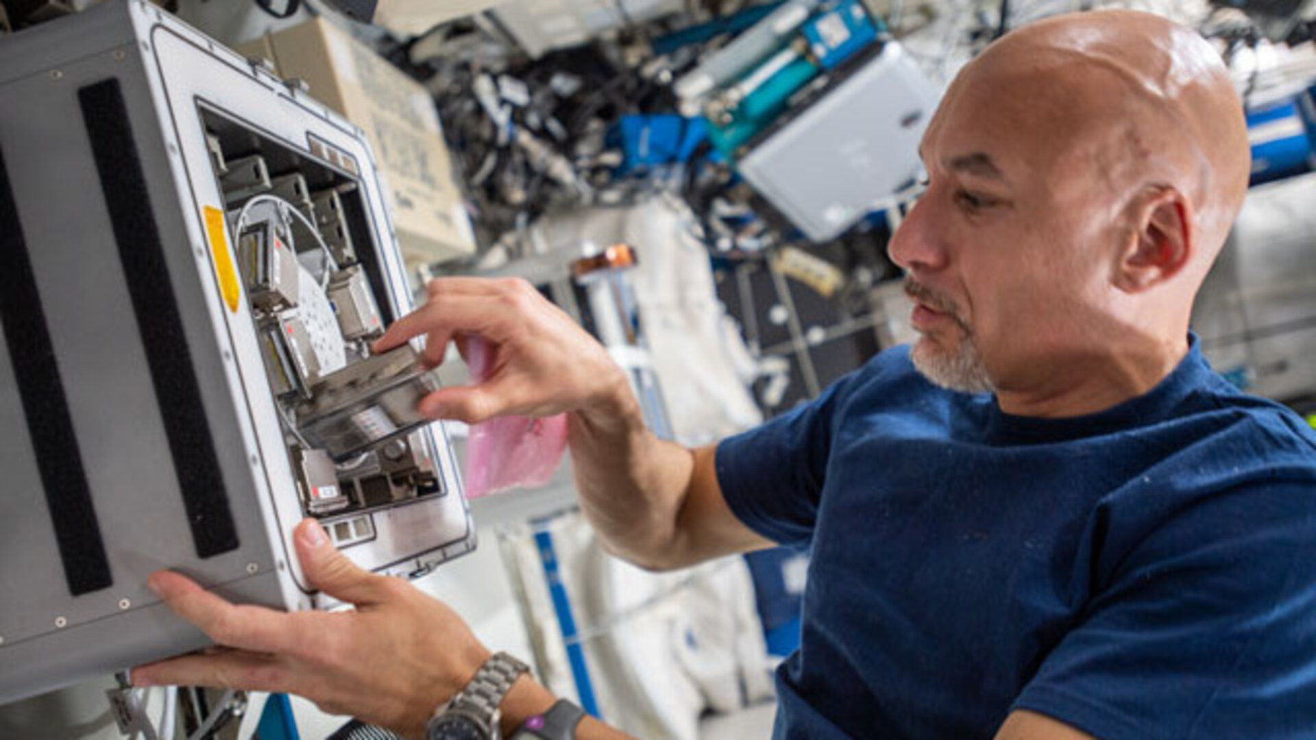 ESA astronaut Luca Parmitano installs a device to test how biofilms grow in altered gravity conditions